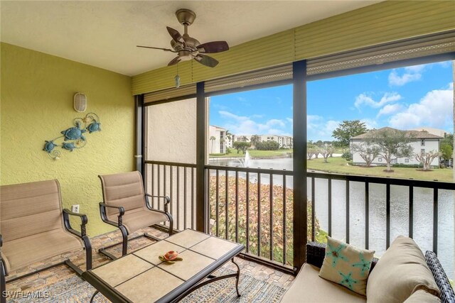 sunroom / solarium with a water view and ceiling fan