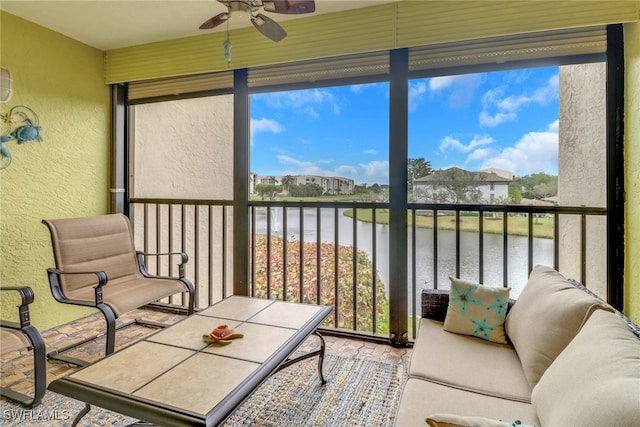 sunroom featuring ceiling fan and a water view