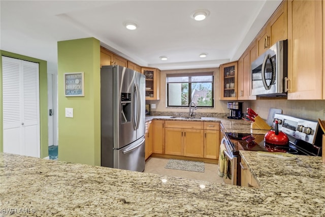 kitchen with sink, light stone countertops, kitchen peninsula, and appliances with stainless steel finishes