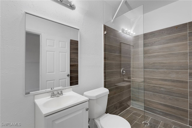 bathroom with vanity, toilet, and tiled shower