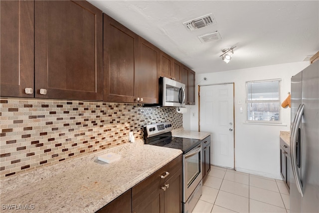 kitchen featuring stainless steel appliances, light tile patterned floors, light stone countertops, decorative backsplash, and dark brown cabinetry