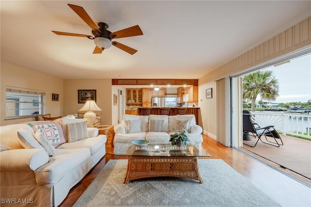 living room featuring a water view, ceiling fan, and wood-type flooring