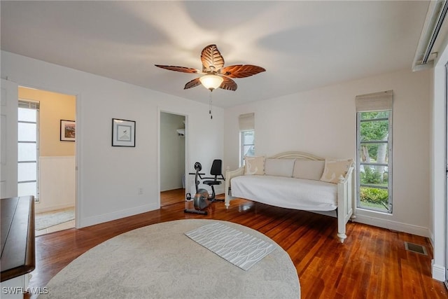 bedroom with a spacious closet, dark hardwood / wood-style floors, and ceiling fan