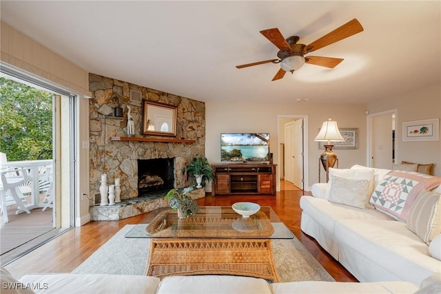 living room featuring hardwood / wood-style flooring, a stone fireplace, and ceiling fan