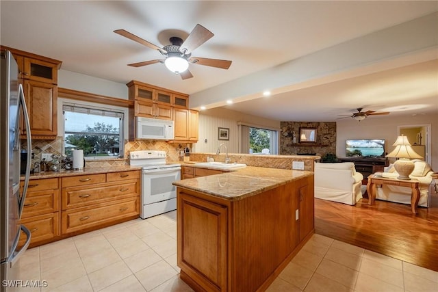 kitchen featuring sink, light tile patterned floors, kitchen peninsula, white appliances, and light stone countertops