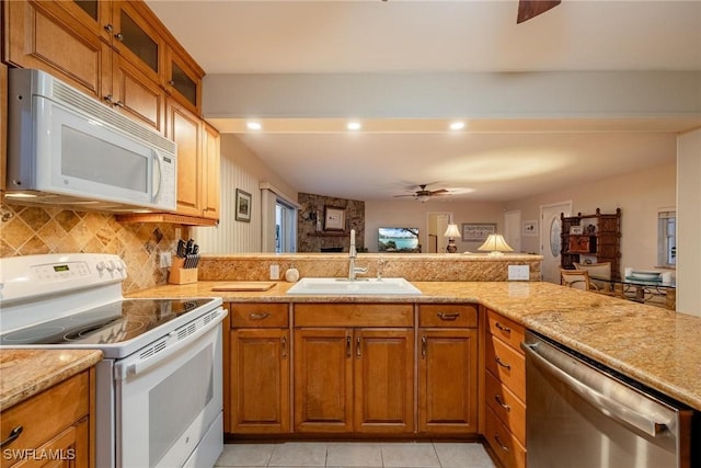 kitchen with light tile patterned flooring, sink, light stone counters, white appliances, and backsplash