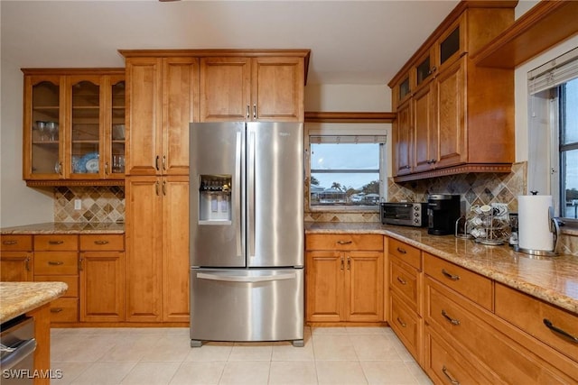 kitchen featuring light stone counters, light tile patterned floors, decorative backsplash, and stainless steel appliances