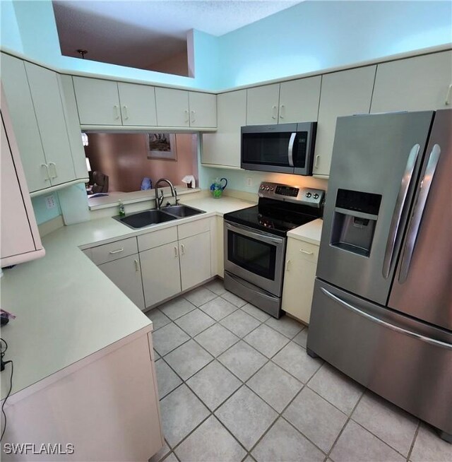 kitchen featuring light tile patterned floors, light countertops, appliances with stainless steel finishes, and a sink