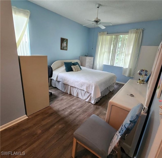 bedroom with dark wood-type flooring, a ceiling fan, and baseboards