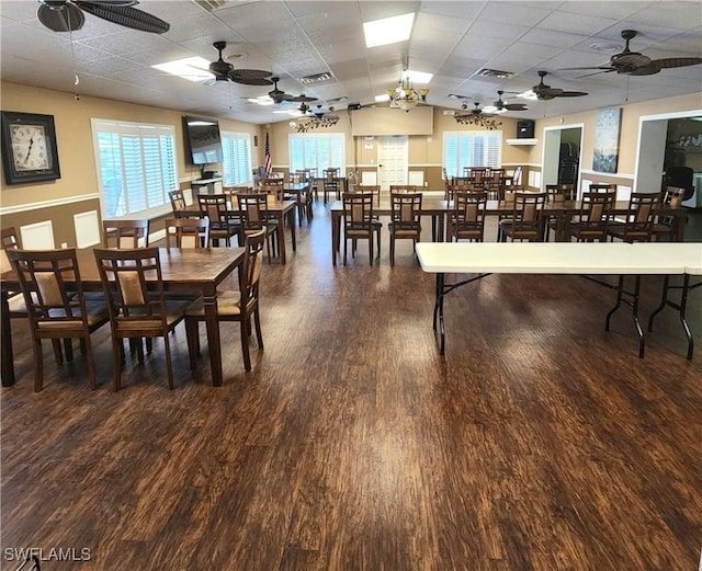 dining space featuring ceiling fan, wood-type flooring, and a drop ceiling