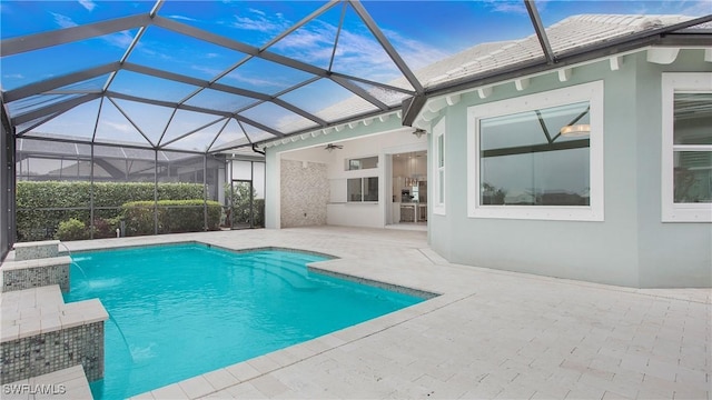 view of pool with ceiling fan, pool water feature, glass enclosure, and a patio area