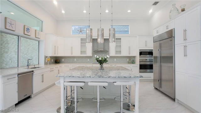 kitchen with white cabinetry, a kitchen island, and built in appliances