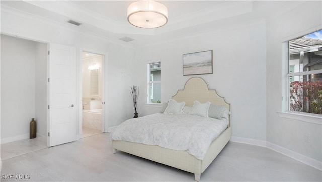 bedroom featuring crown molding, ensuite bath, and a tray ceiling