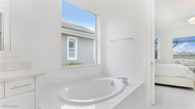 bathroom featuring vanity and tiled bath