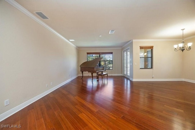 spare room featuring crown molding, dark wood-type flooring, and an inviting chandelier