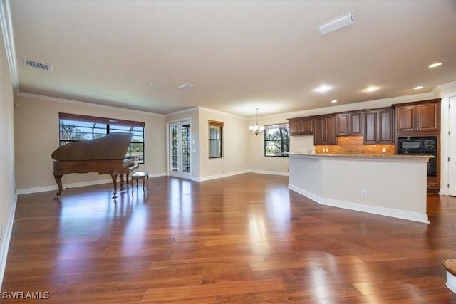 28830 Kiranicola Ct, Bonita Springs, FL 34135 - kitchen featuring a chandelier, black microwave, crown molding, dark wood-type flooring, and light countertops