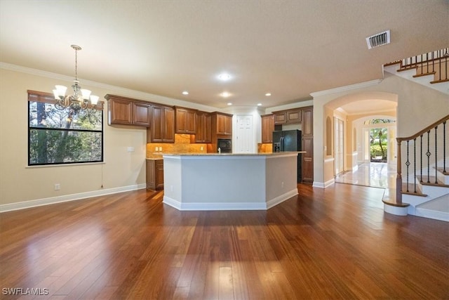 kitchen with black fridge, crown molding, a center island, dark hardwood / wood-style floors, and pendant lighting