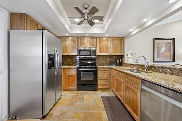 kitchen featuring sink, light stone counters, crown molding, appliances with stainless steel finishes, and a tray ceiling