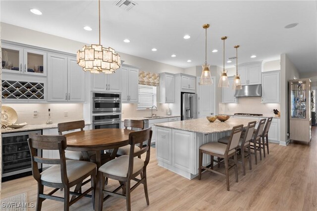 kitchen featuring sink, hanging light fixtures, stainless steel appliances, wine cooler, and a kitchen island