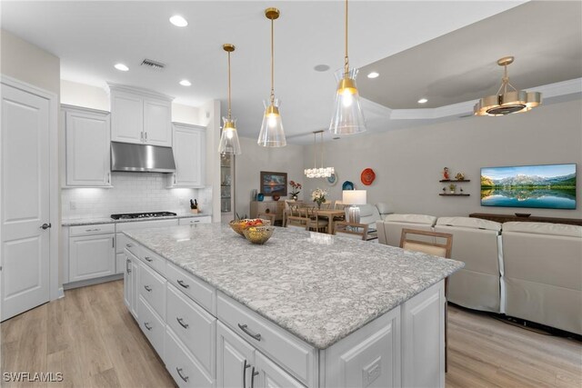 kitchen with white cabinetry, pendant lighting, washer and dryer, and a kitchen island