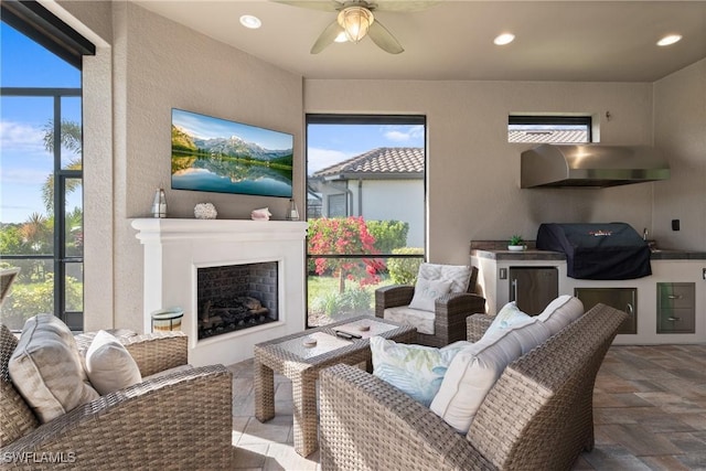 interior space featuring ceiling fan, plenty of natural light, and an outdoor fireplace