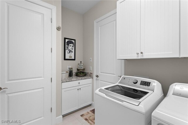 laundry area featuring light tile patterned floors, cabinets, and washer and dryer