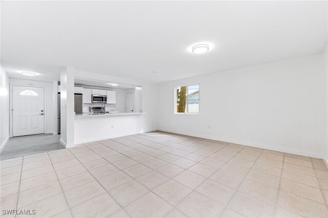 unfurnished living room featuring baseboards and light tile patterned floors