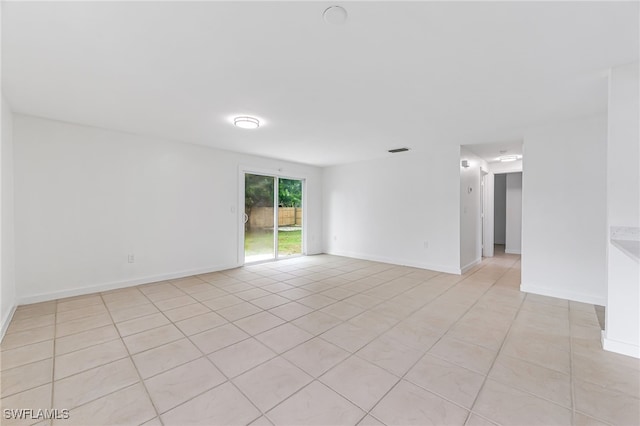 empty room featuring light tile patterned floors, visible vents, and baseboards