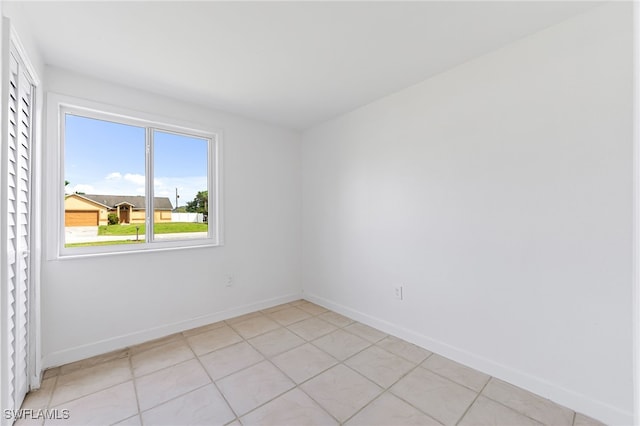 spare room with light tile patterned floors and baseboards