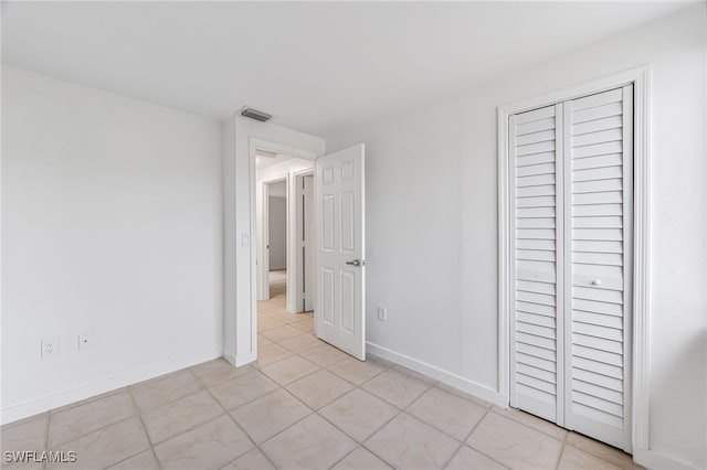 unfurnished bedroom with a closet, visible vents, and baseboards