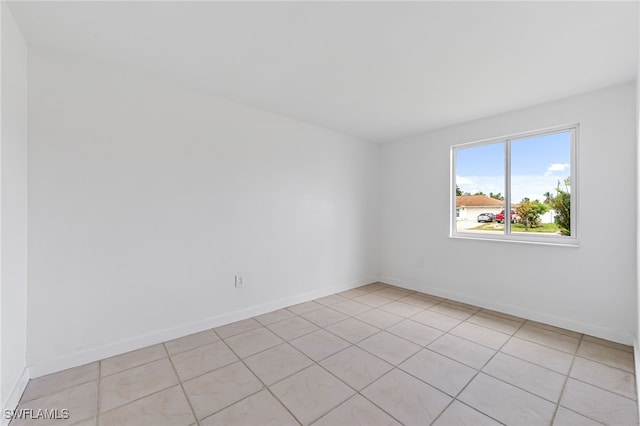 unfurnished room with light tile patterned flooring and baseboards