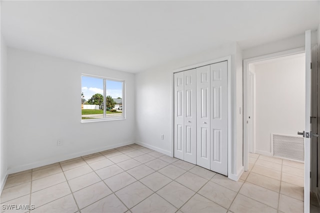 unfurnished bedroom with light tile patterned floors, a closet, visible vents, and baseboards