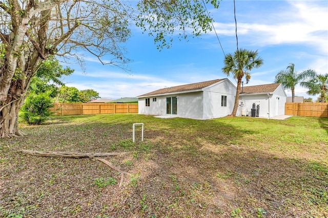 back of house with a lawn, a fenced backyard, and stucco siding