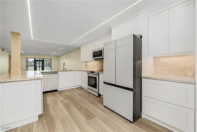 kitchen with sink, white cabinets, light hardwood / wood-style flooring, backsplash, and stainless steel appliances