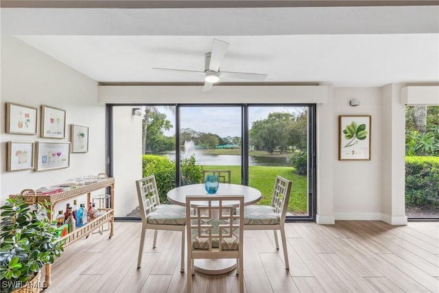 dining room with light hardwood / wood-style flooring, ceiling fan, and a water view