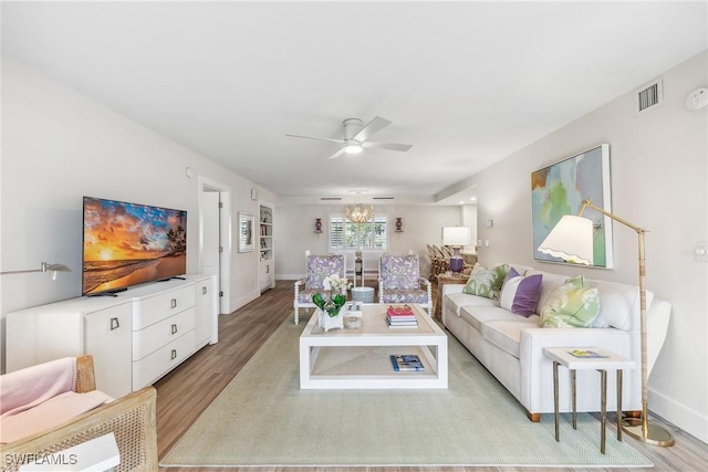 living room featuring ceiling fan with notable chandelier and light hardwood / wood-style floors