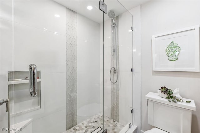 bathroom featuring toilet and a shower with shower door