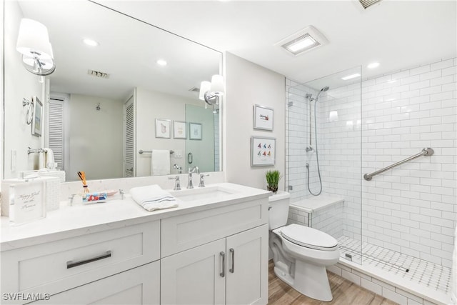 bathroom with hardwood / wood-style flooring, vanity, a shower with door, and toilet