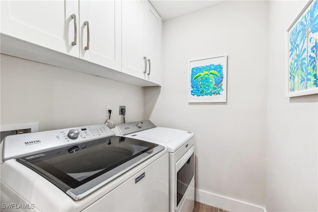 laundry room featuring separate washer and dryer and cabinets