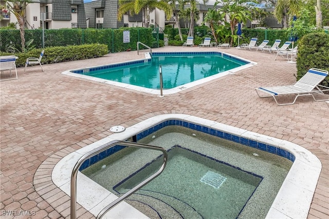 view of swimming pool featuring a hot tub and a patio area