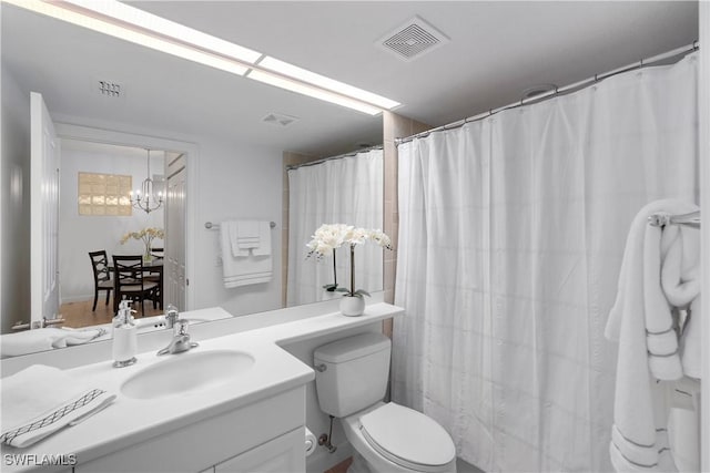 bathroom with toilet, a notable chandelier, and vanity