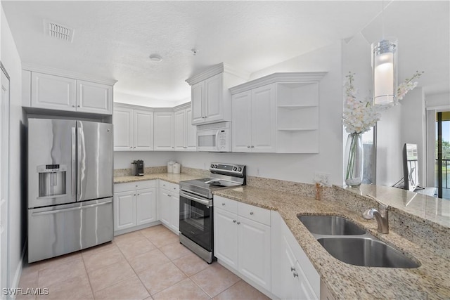 kitchen featuring appliances with stainless steel finishes, light tile patterned floors, white cabinets, sink, and light stone counters