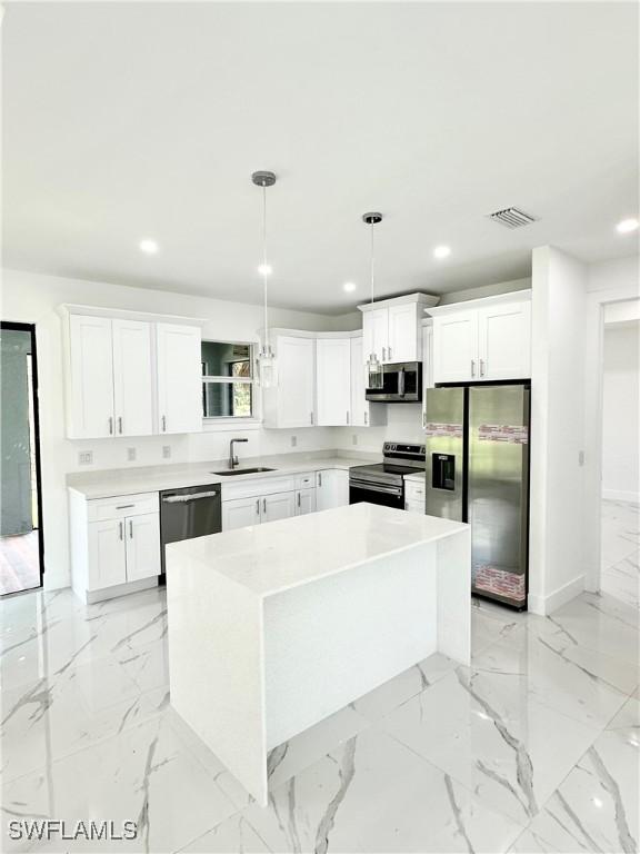 kitchen with hanging light fixtures, sink, white cabinets, a center island, and stainless steel appliances