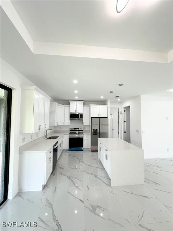 kitchen with sink, white cabinetry, stainless steel appliances, and a kitchen island