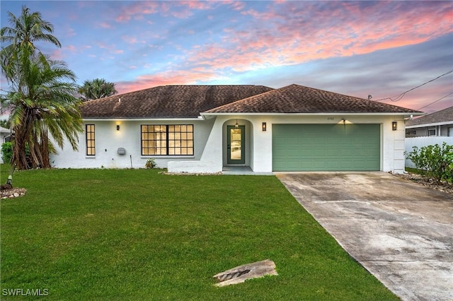 view of front facade with driveway, an attached garage, a lawn, and stucco siding