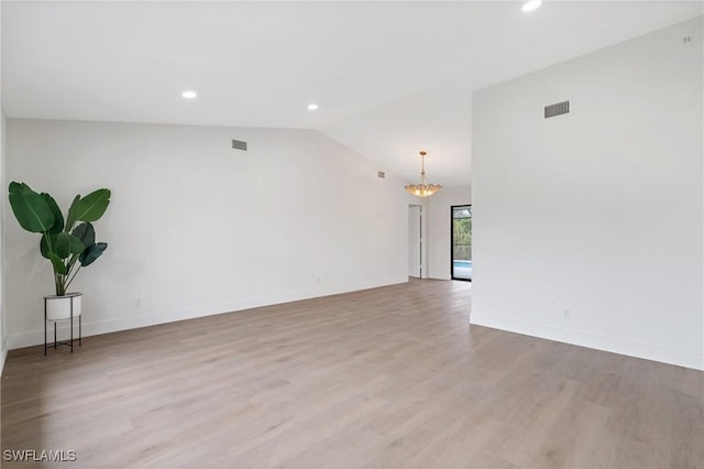 unfurnished room with lofted ceiling, a notable chandelier, light wood-style flooring, and baseboards