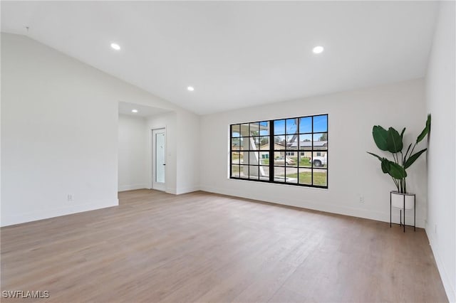 spare room with vaulted ceiling, recessed lighting, baseboards, and light wood-style floors