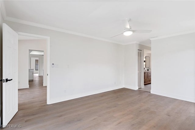 spare room featuring crown molding, baseboards, ceiling fan, and wood finished floors