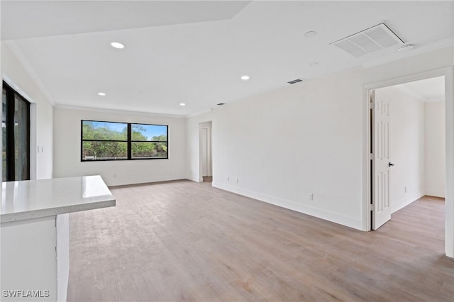 unfurnished living room featuring light wood-type flooring, baseboards, visible vents, and crown molding