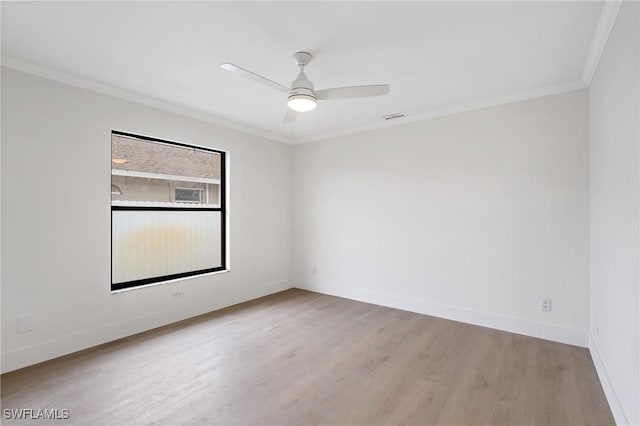 spare room with ceiling fan, wood finished floors, visible vents, baseboards, and ornamental molding